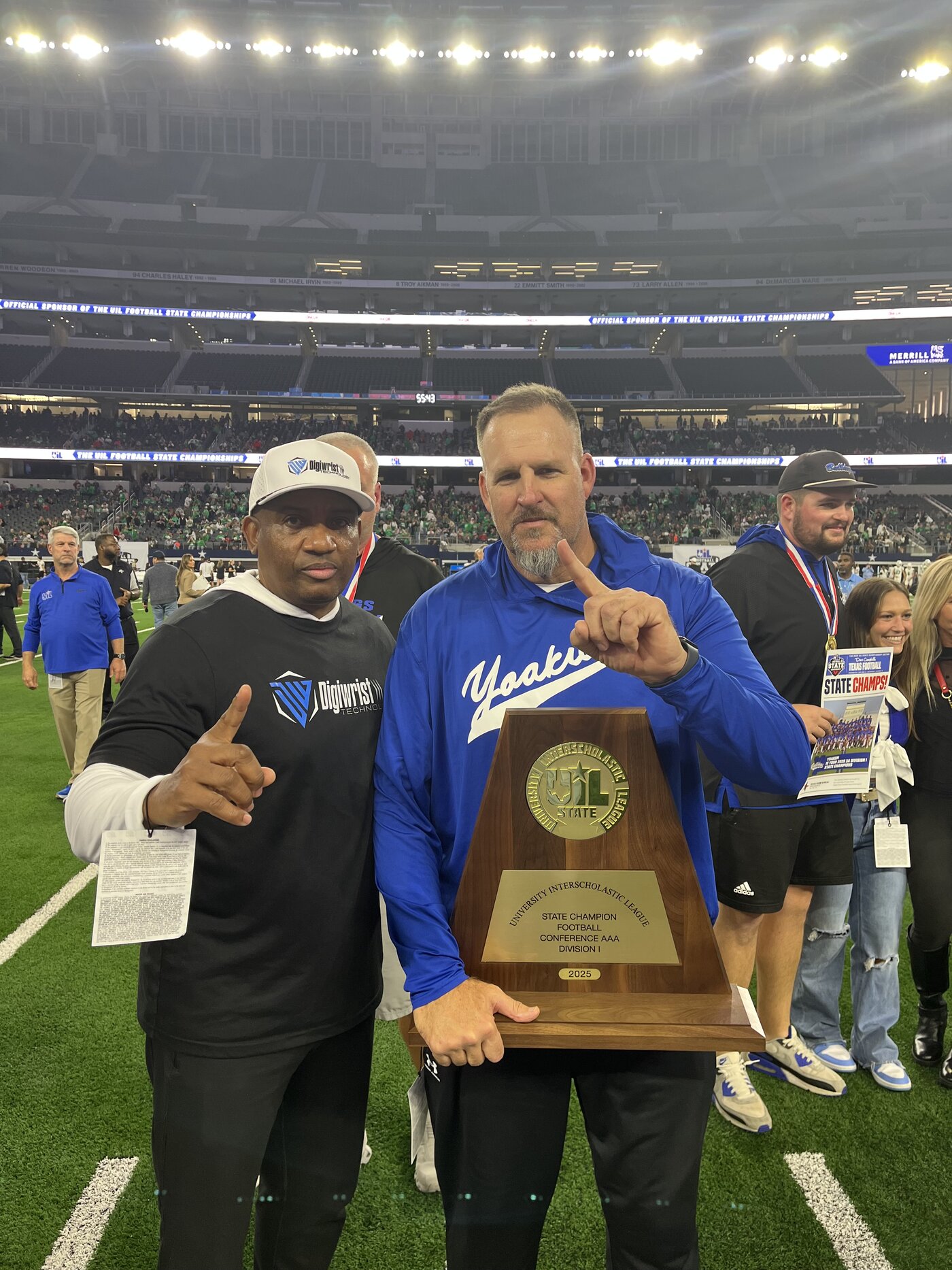 Coaches with the state championship trophy on the field
