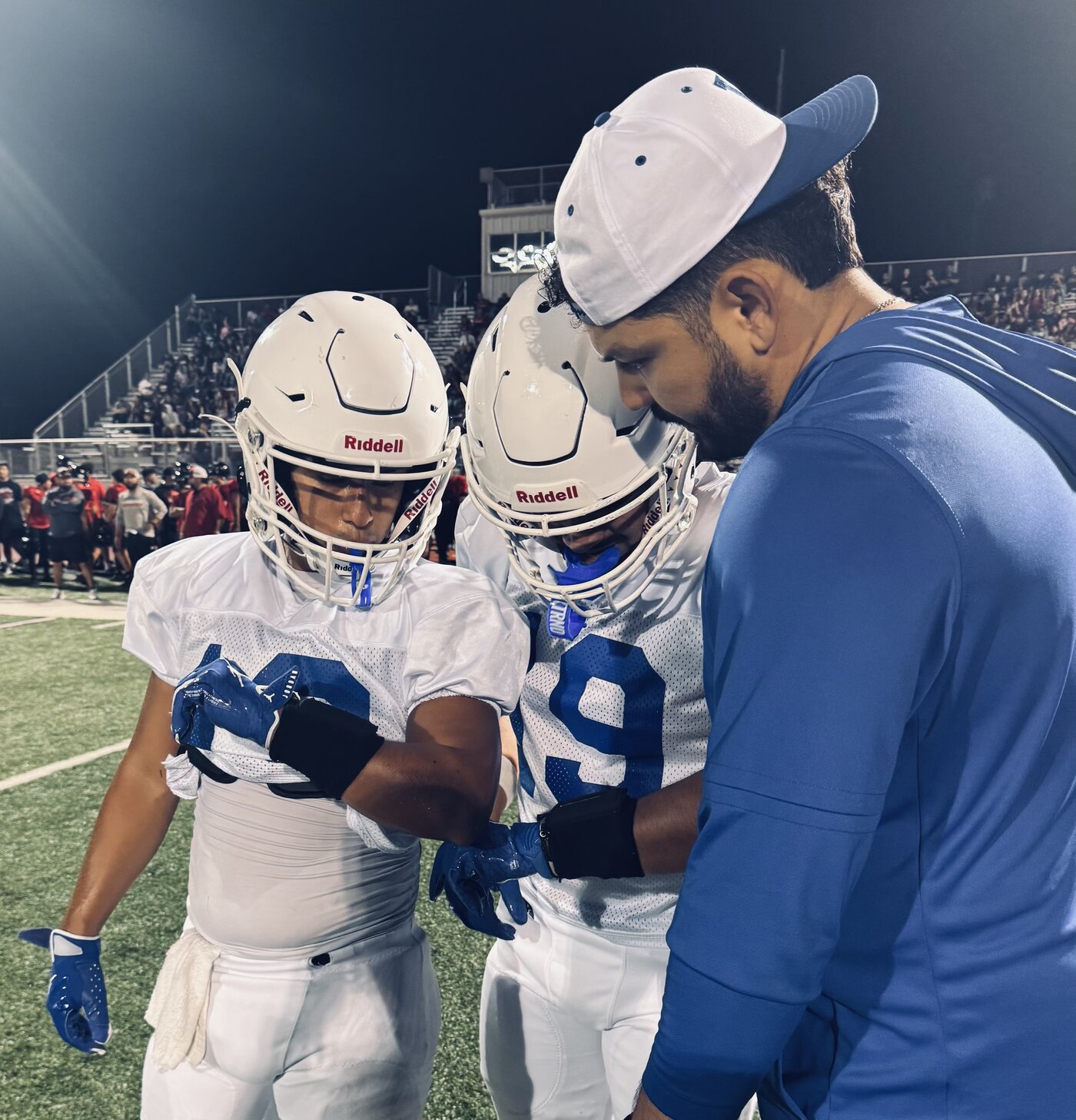 Coach calling the play with helmeted players checking their wrists